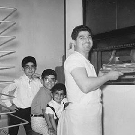 Gaspare and boys by oven with pizza.